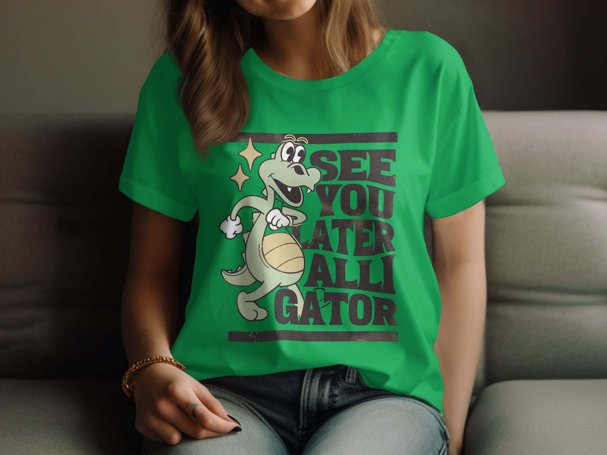 A person relaxes on a couch in a Garment Graphics Alligator T-Shirt, showcasing a cartoon alligator with a basketball and the phrase See you later alligator. Sporting long hair and a bracelet on their right wrist, they exemplify the comfort and style of Womens Sizing.