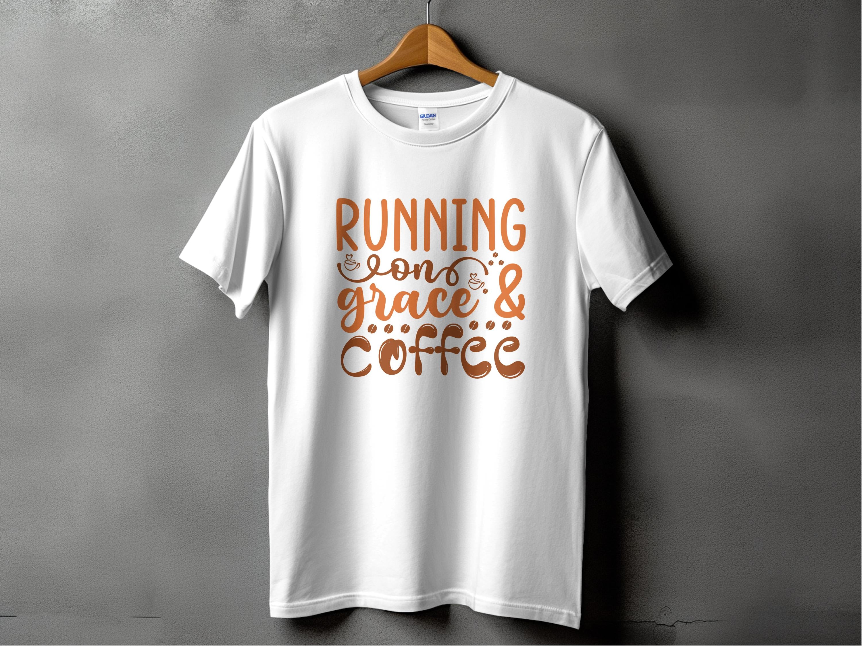 A stylish Garment Graphics T-shirt hangs on a gray wall, displaying the motivational phrase Running on grace & coffee in elegant brown lettering.