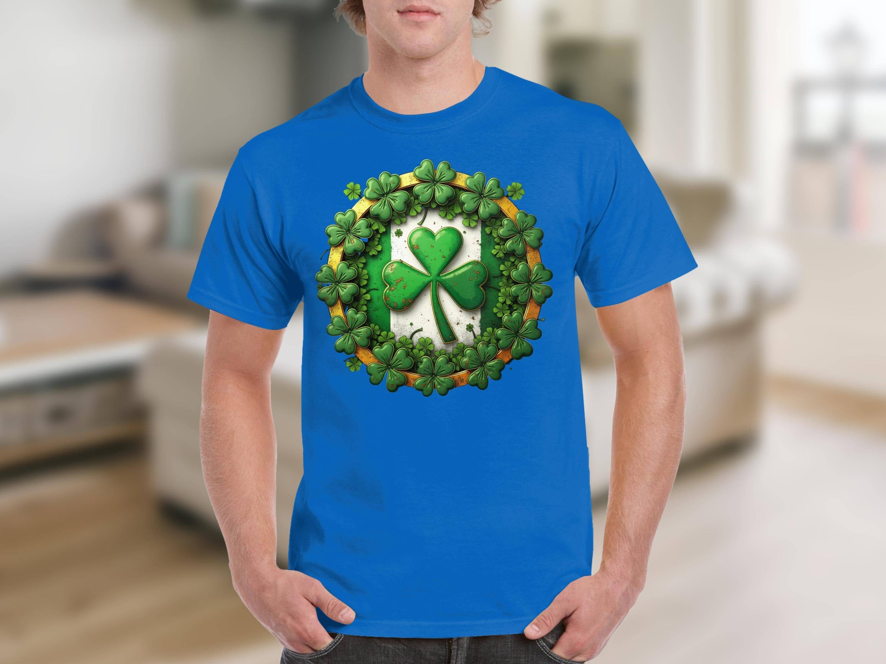 A person is wearing a Garment Graphics T-shirt in vibrant blue, showcasing a green shamrock clover surrounded by other shamrocks. The background reveals a blurred interior with neutral tones, embodying the St. Patricks Day spirit.