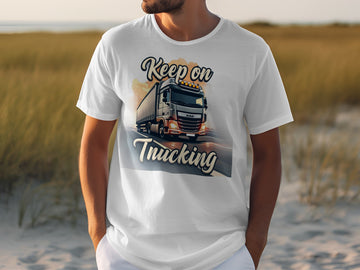 A truck enthusiast wears a Garment Graphics white t-shirt with a large truck graphic on a road, Keep on Trucking text, and a grassy field under a clear sky backdrop.