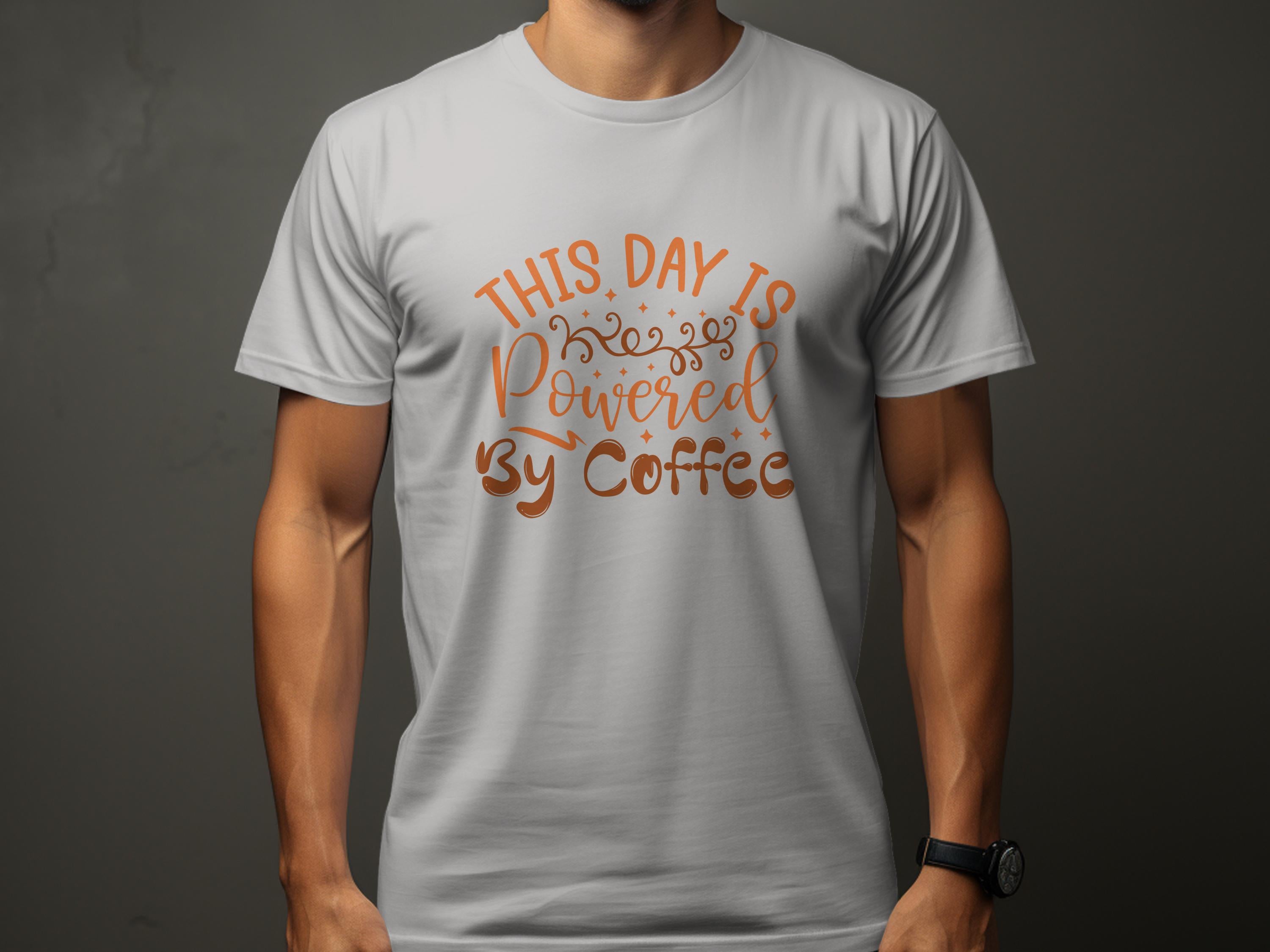 A cheerful person in a Garment Graphics classic fit white T-shirt with This Day is Powered by Coffee in stylish brown text stands against a plain gray background, arms relaxed.