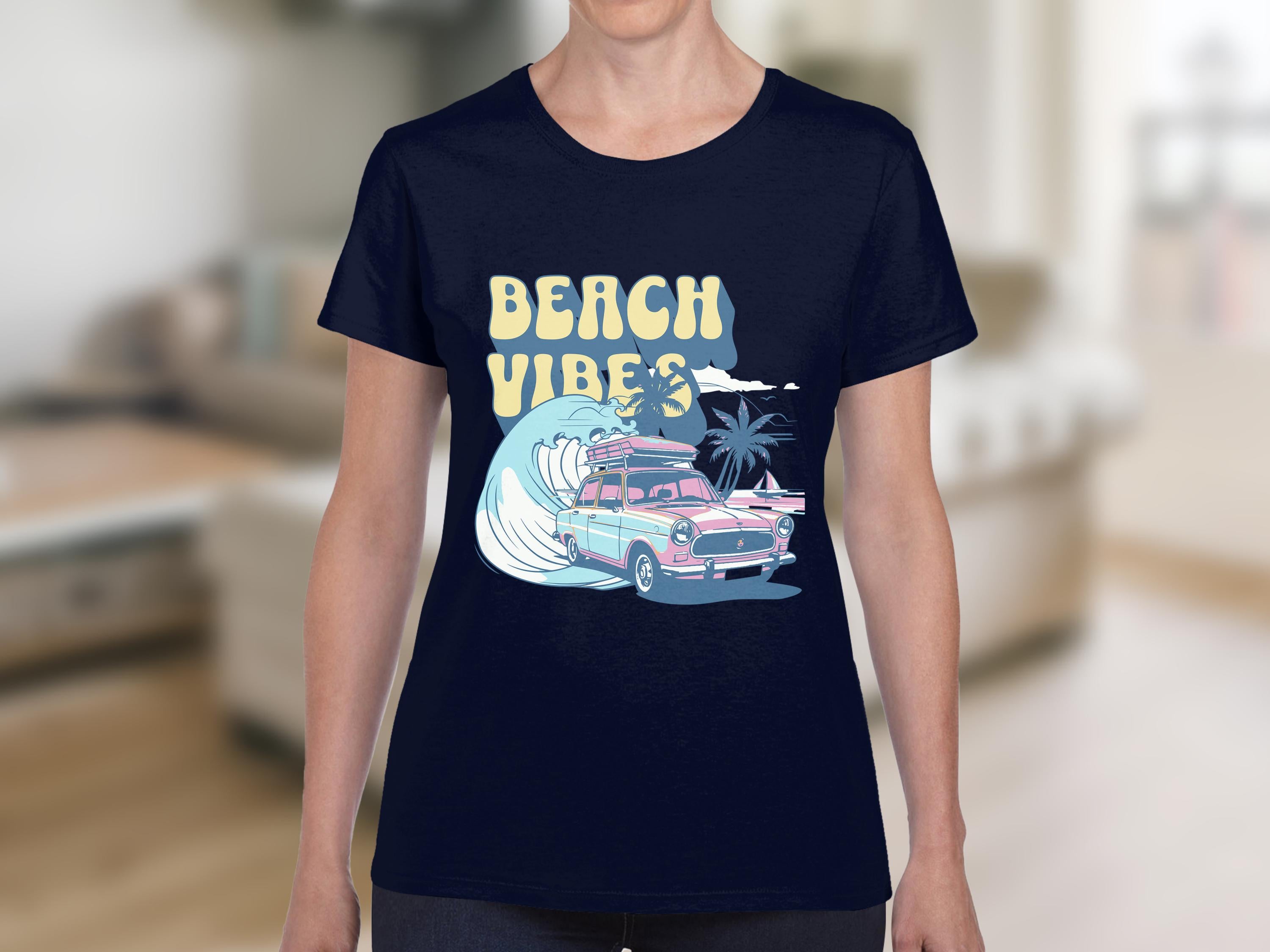 Someone is sporting a navy retro T-shirt by Garment Graphics, featuring a pink vintage car with surfboards, waves, and palm trees. Beach Vibes is joyfully displayed above the scene. Indoors, blurred furniture highlights the coastal allure.