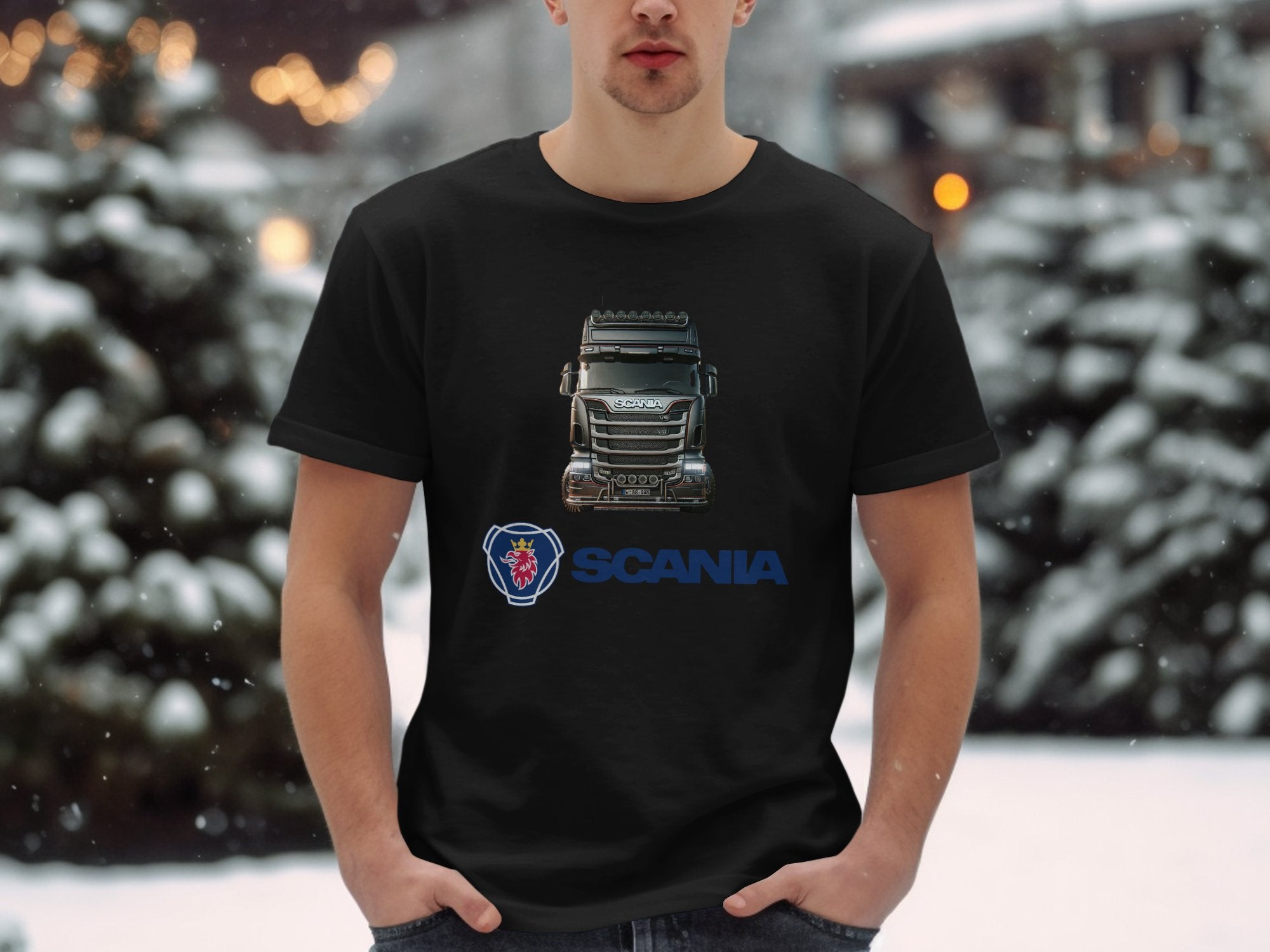 In a snowy setting, a person proudly wears a Garment Graphics black T-shirt loved by truck fans. It showcases an image of a Scania truck with its logo underneath. Standing with hands in pockets, they pose against snow-covered trees.