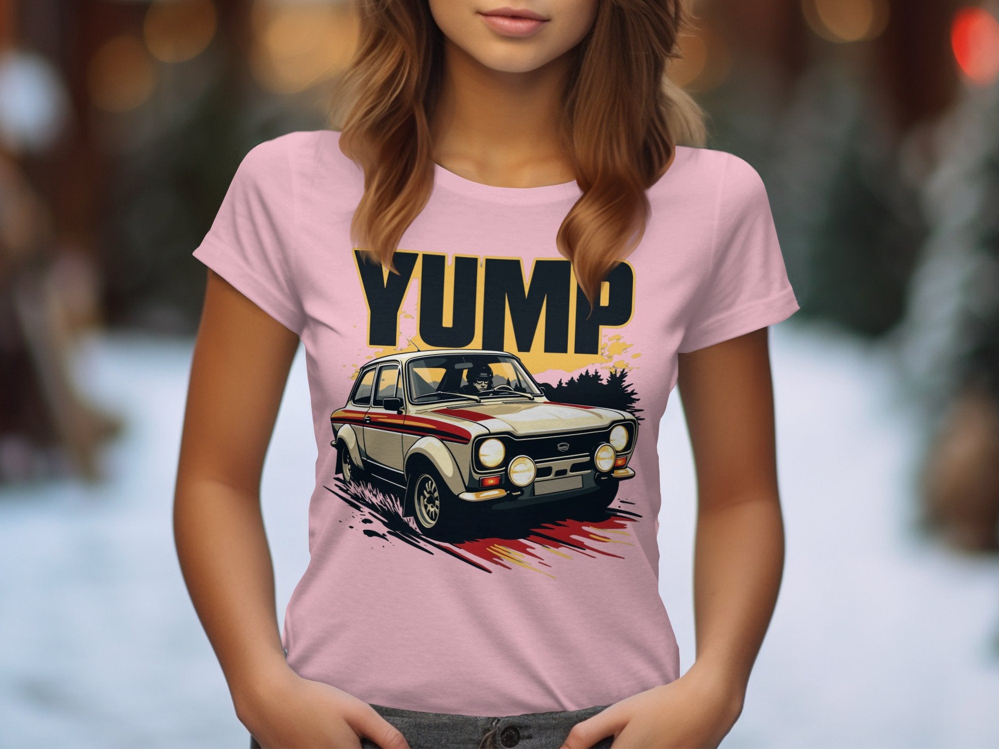 A woman wears a Garment Graphics pink t-shirt featuring a vintage car graphic with YUMP prominently displayed above. The retro design pops against a softly blurred outdoor background, capturing vintage racing charm.