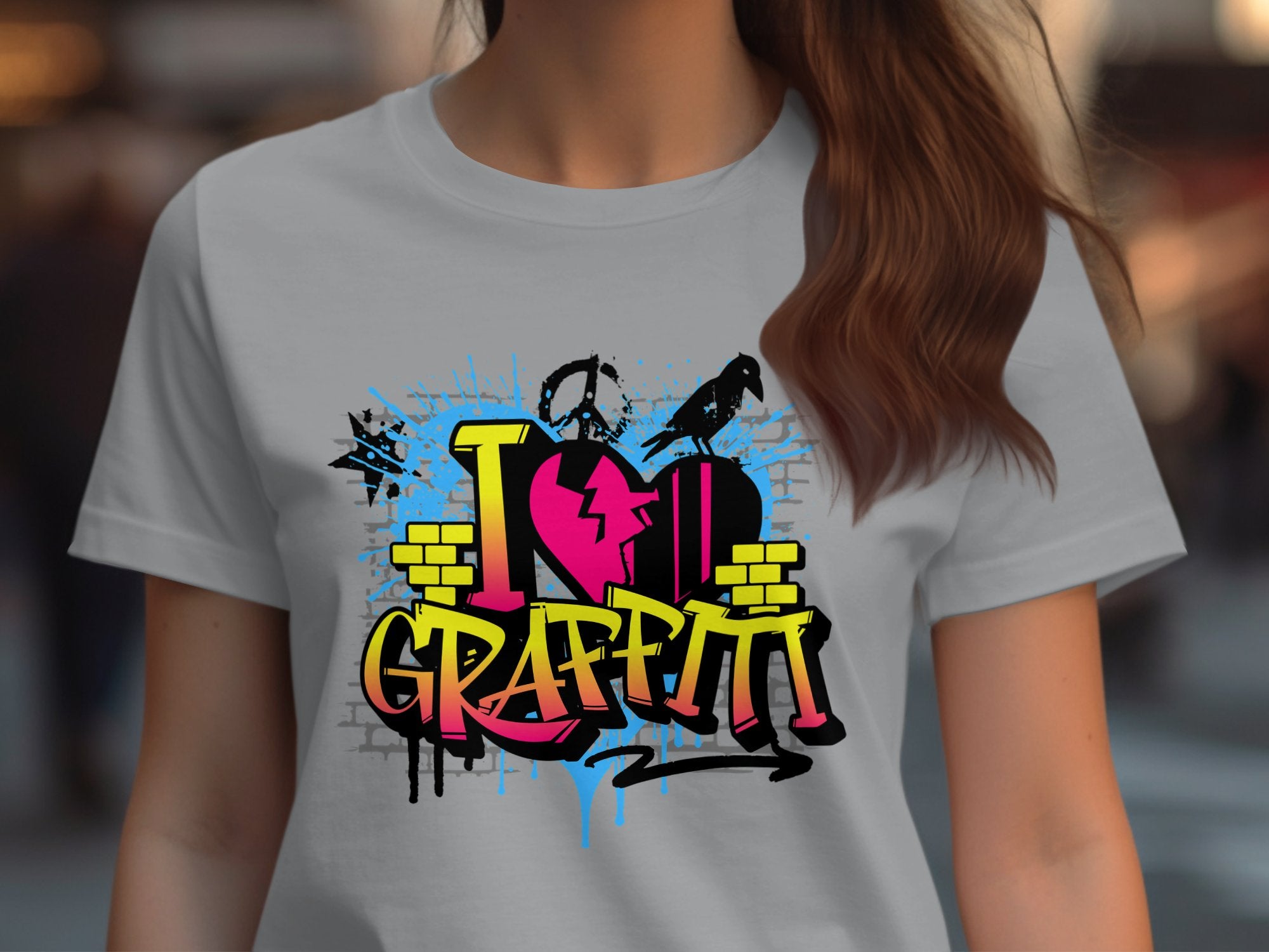 A person wearing a Garment Graphics light gray T-shirt with urban I Love Graffiti designs in vibrant pink, yellow, and blue, featuring paint splatters and a heart icon.