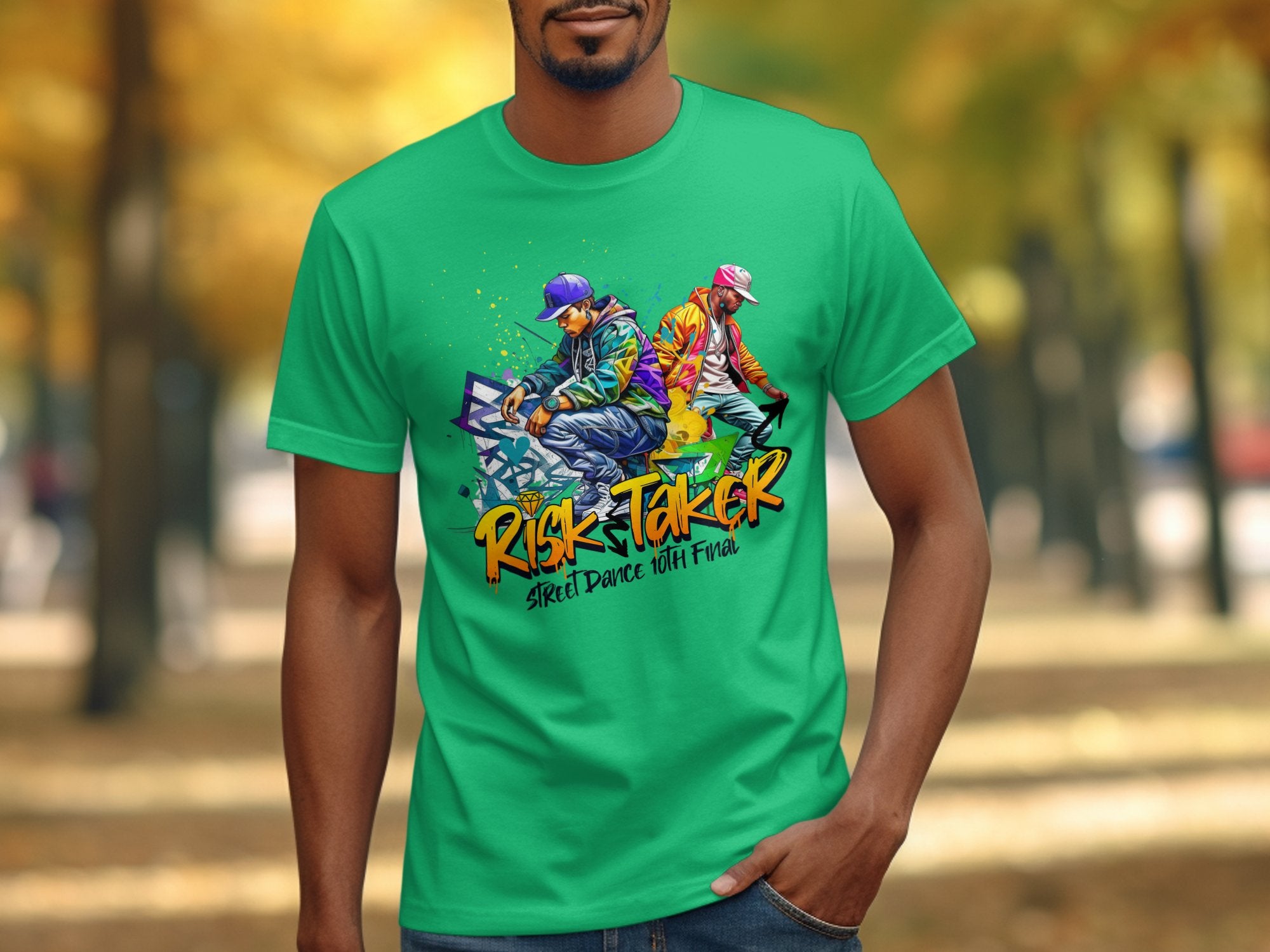 A man wears a Garment Graphics T-shirt in bright green, adorned with artistic designs of two street dancers and graffiti-style text that reads Risk Taker Street Dance with Flair, set against a softly blurred backdrop of autumn trees for a seasonal touch.