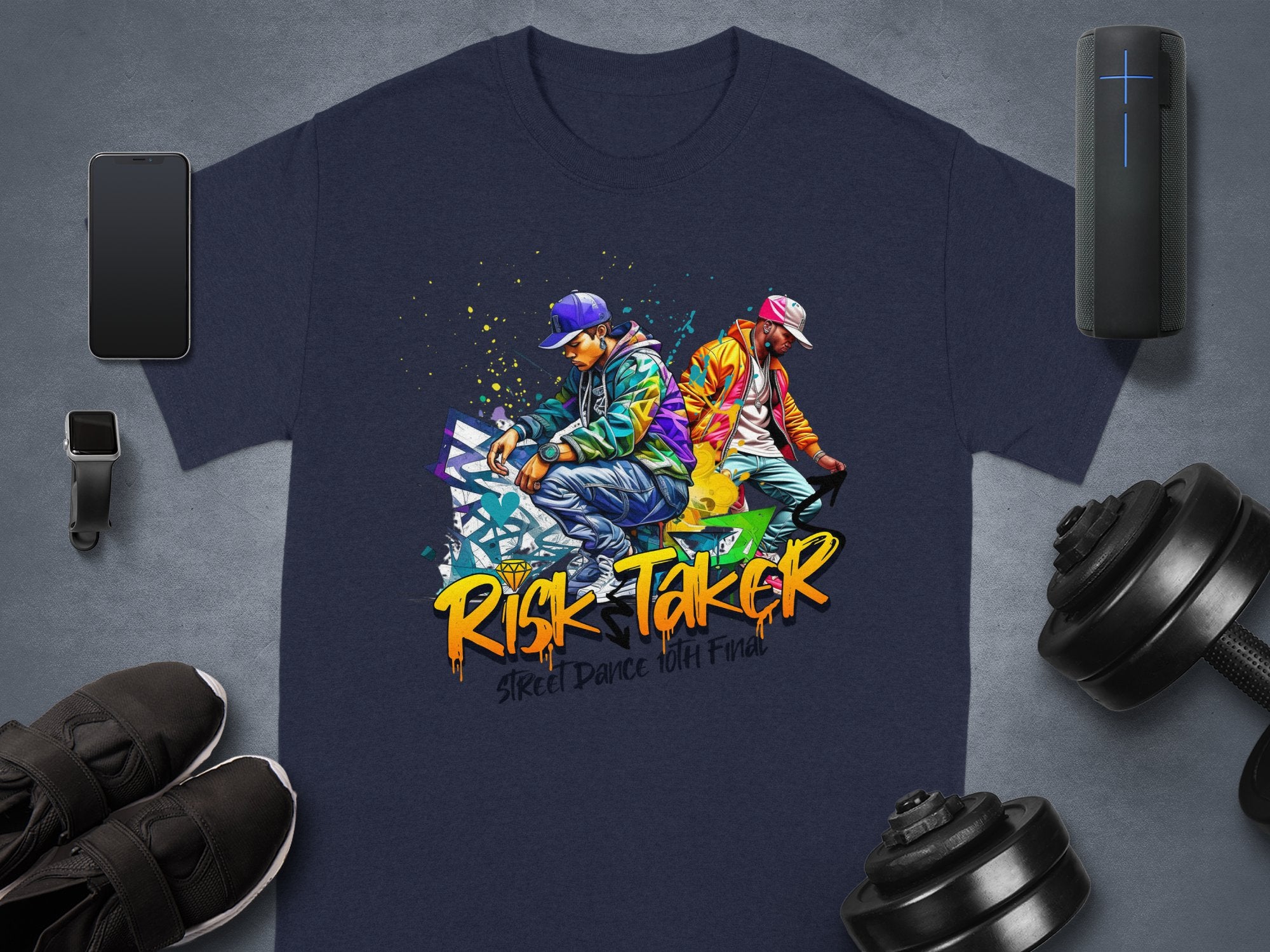 The Garment Graphics dark blue T-shirt features street dancers against vibrant graffiti. It celebrates street dance culture with Risk-Taker and Street Dance Wild Final phrases, surrounded by fitness items like weights and shoes, highlighting its artistic design tribute.