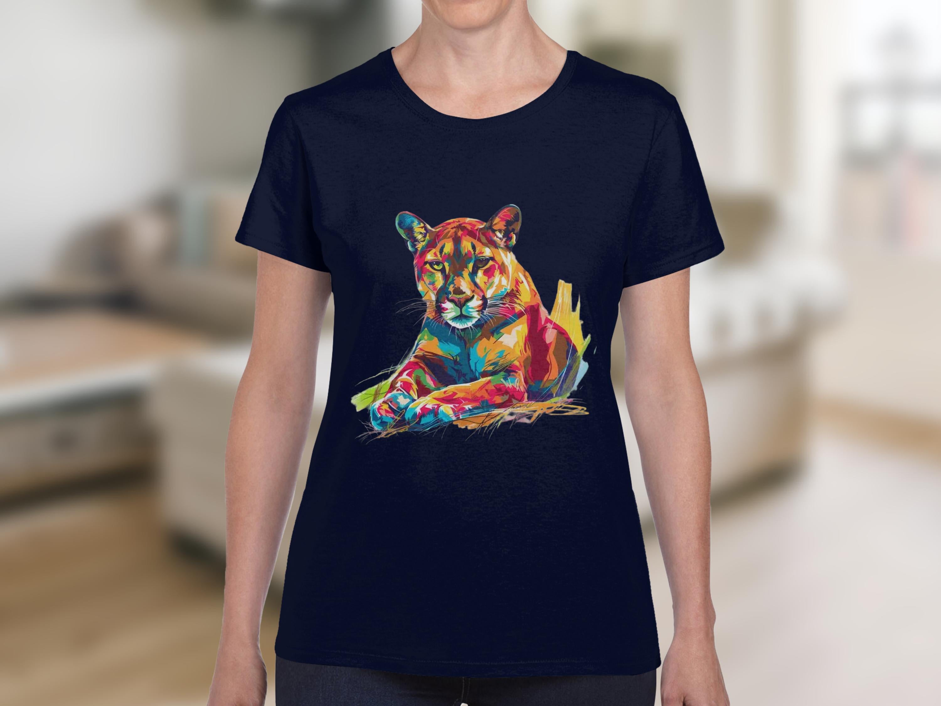 A person in a navy blue Garment Graphics T-shirt featuring a vibrant puma design relaxes in a softly blurred, modern living room setting.