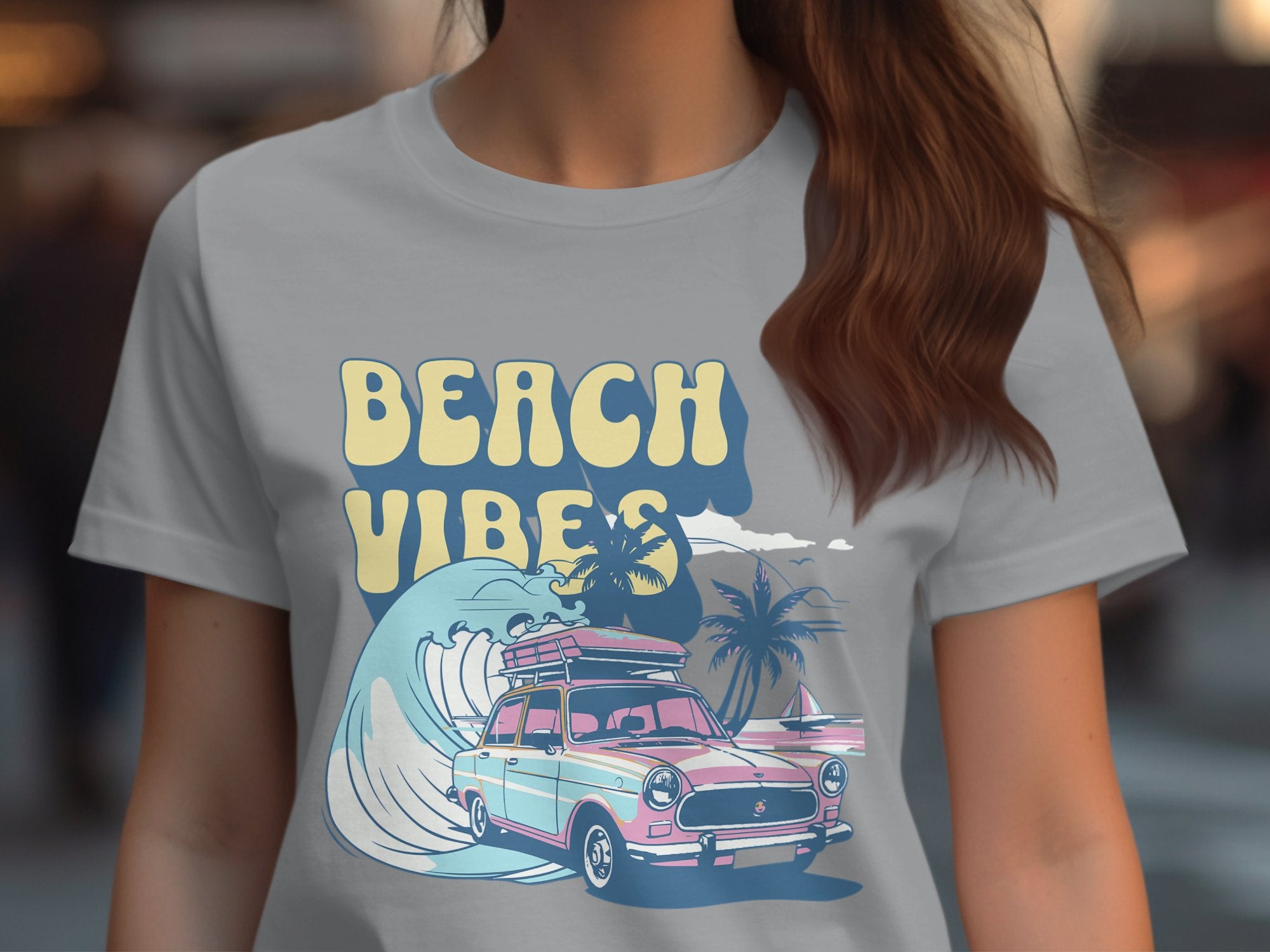 Someone wearing a Garment Graphics light gray retro t-shirt featuring Beach Vibes with a vintage car loaded with surfboards, alongside waves and palm trees.