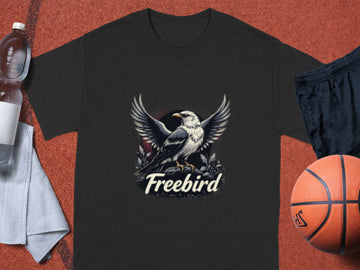 Garment Graphics presents a dark gray T-shirt adorned with an eagle in flight and the iconic Freebird logo, perfect for casual wear. Displayed on a red surface, it pairs well with a water bottle, white towel, black shorts, and basketball.