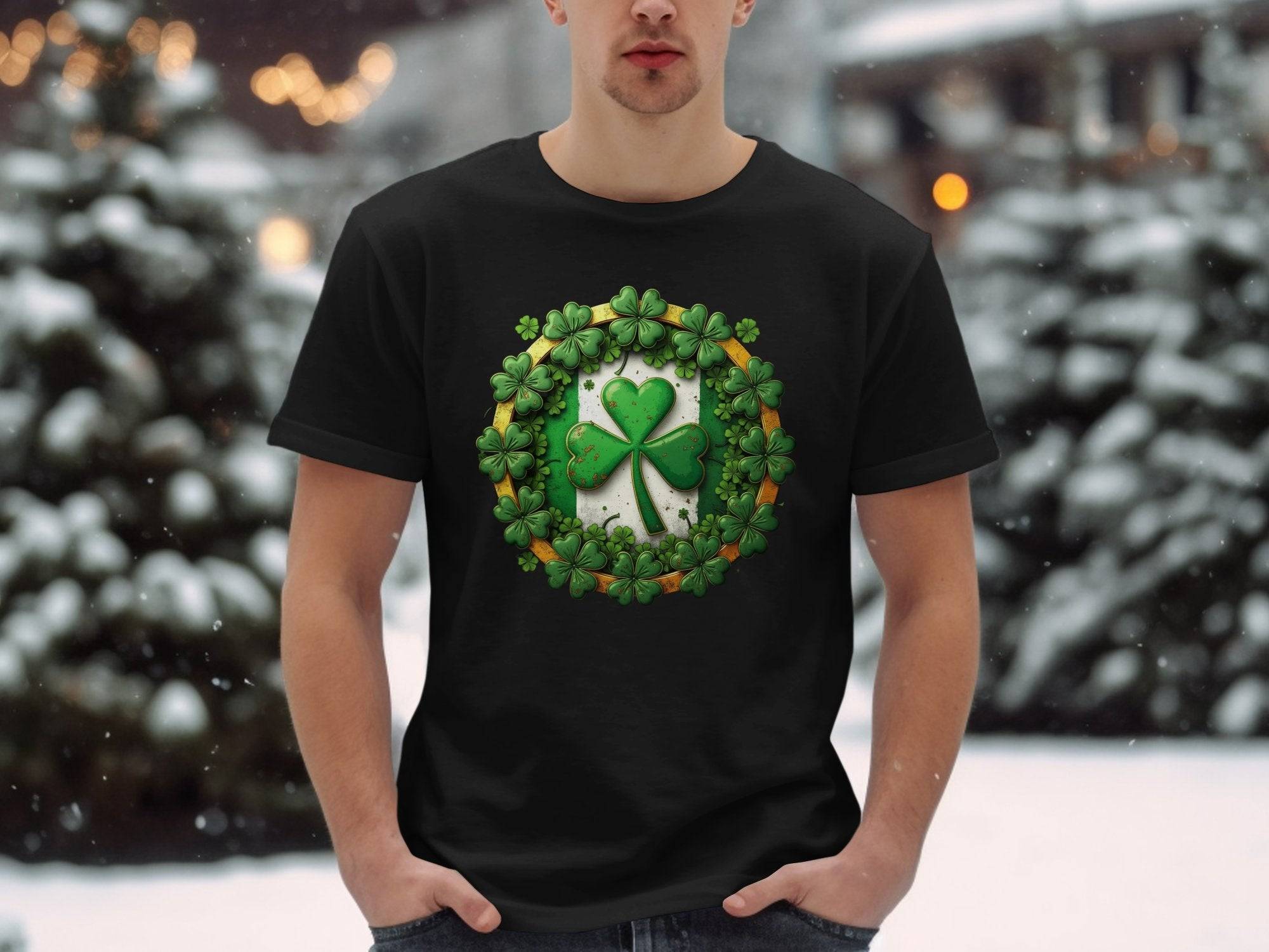 Against a snowy backdrop with blurred lights and snow-covered trees, someone stands wearing a black T-shirt by Garment Graphics. Its decorated with a large shamrock clover encircled by smaller clovers, perfect for celebrating St Patricks Day.