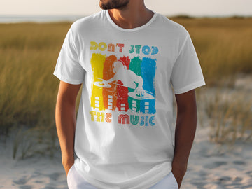 A man wearing a Garment Graphics white t-shirt featuring a vibrant DJ graphic and the phrase Dont Stop the Music stands in a grassy area, attracting music lovers attention.