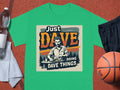 A classic fit graphic tee by Garment Graphics: green with a mustached man dining at a table. Features bold Just Dave Doing Dave Things text. Displayed on a basketball court with accessories like a basketball, water bottle, and shorts nearby.