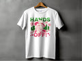 Garment Graphics t-shirt, white on a hanger, showcases a striking design of a hatted figure with two flowers. HANDS OFF! appears in green and red text along with Wild and J. Red hearts are integrated into the classic fit Hands Off T-Shirts design.