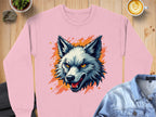 A pink Garment Graphics graffiti style sweatshirt showcases a stylized wolfs head with intense fiery orange eyes and a bold orange background. It rests on a wooden surface beside a denim jacket and latte.