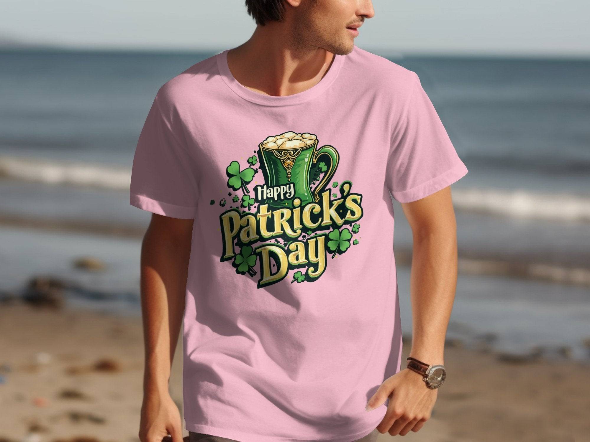 On a serene beach, someone makes a bold statement wearing a festive pink Garment Graphics T-shirt that says Happy Patricks Day, adorned with beer mugs and shamrocks.