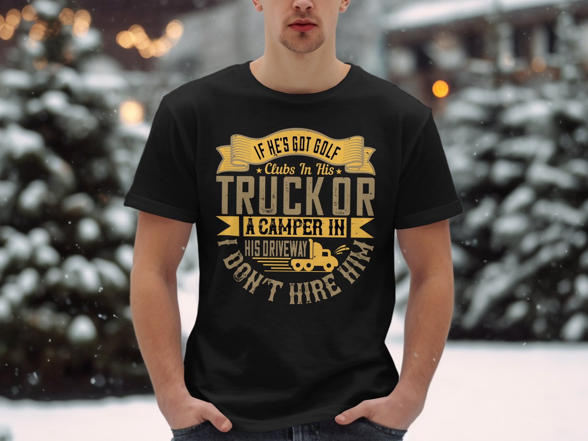 Against a snowy backdrop, a person wears a Garment Graphics black T-shirt featuring the humorous quote: If hes got golf clubs in his truck or a camper in his driveway, dont hire him. With gold and beige text, its an ideal gift for those who appreciate humor.