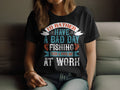 Sporting a Garment Graphics black fishing T-shirt with Id rather have a bad day fishing than a good day at work printed in diverse fonts and colors, someone sits on a couch, their hair partially hiding their face—a true fishing enthusiast.