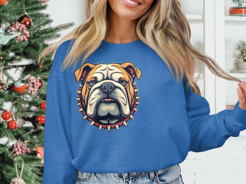 A person in a Garment Graphics blue unisex sweatshirt with a bulldog graphic near a decorated Christmas tree. The stylized bulldog head features a spiked collar, adding flair to the festive scene, though the persons face is partially out of frame.