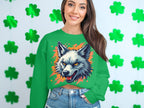 A woman in a bold Garment Graphics sweater featuring a fierce wolf graphic stands in front of a white wall with green shamrocks. Her long brown hair highlights her wild side, and she pairs the striking top with denim shorts.
