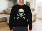 Someone is donning a bold, edgy black sweatshirt from Garment Graphics with a skull and crossbones design. The background is a softly blurred interior room featuring light-colored furniture.