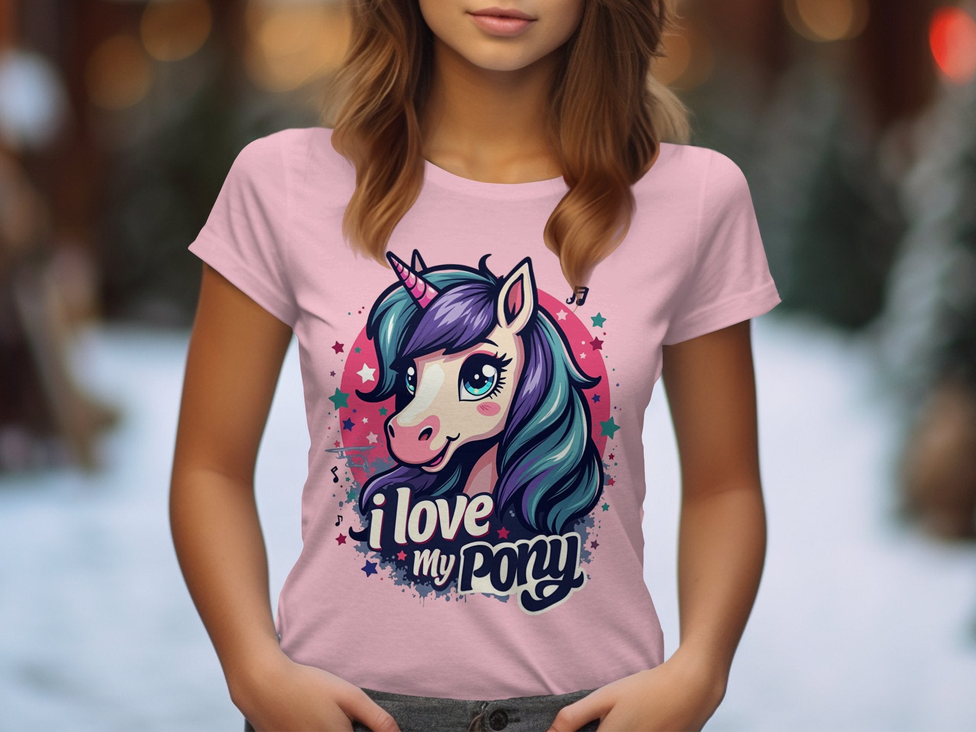 A woman wears a light pink Garment Graphics T-shirt featuring a vibrant unicorn and I Love My Pony. Ideal for unicorn lovers, it stands out against the blurred backdrop of a tree-lined path.