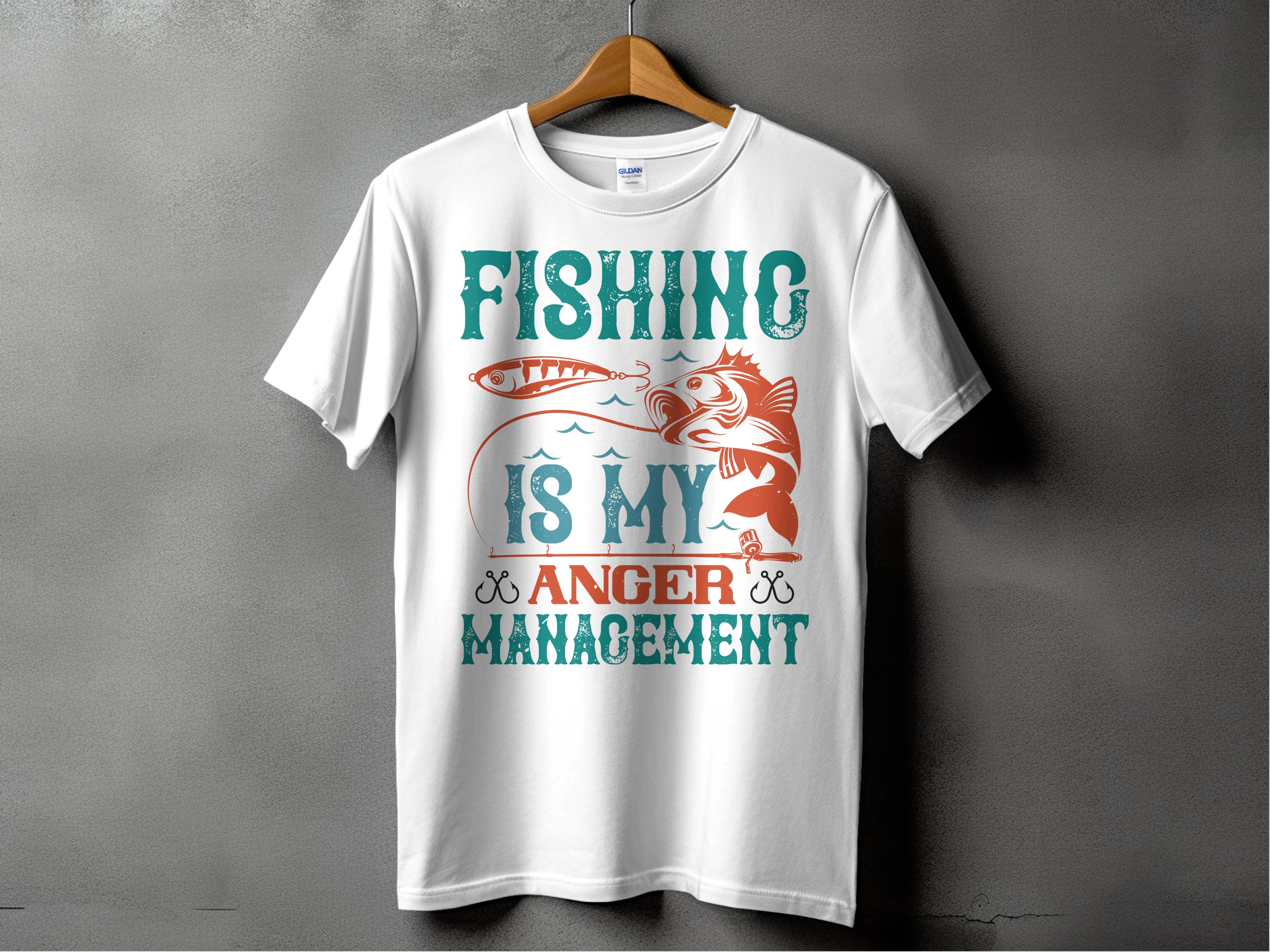 A white fishing T-shirt from Garment Graphics hangs on a wooden hanger against a gray background, featuring the bold design Fishing Is My Anger Management with teal and orange fish and lure images, ideal for any fishing enthusiast.