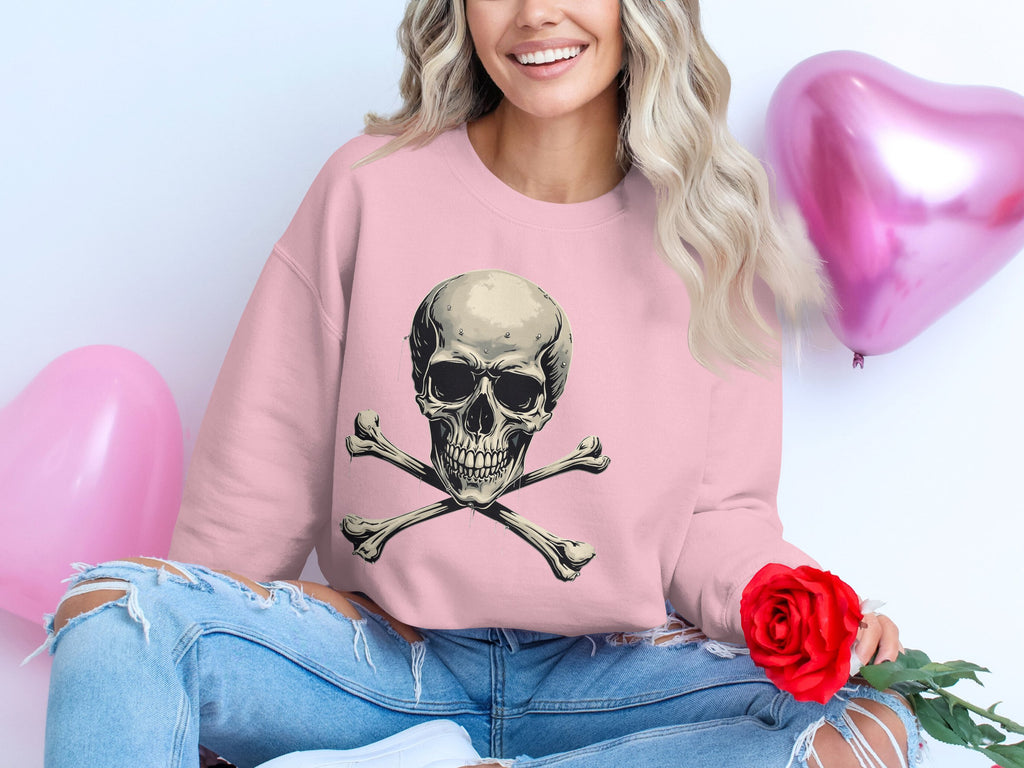 Dressed in Garment Graphics pink unisex skull and crossbones sweatshirt, the person holds a red rose, seated next to two heart-shaped balloons. They pair this look with ripped jeans and flowing wavy hair.