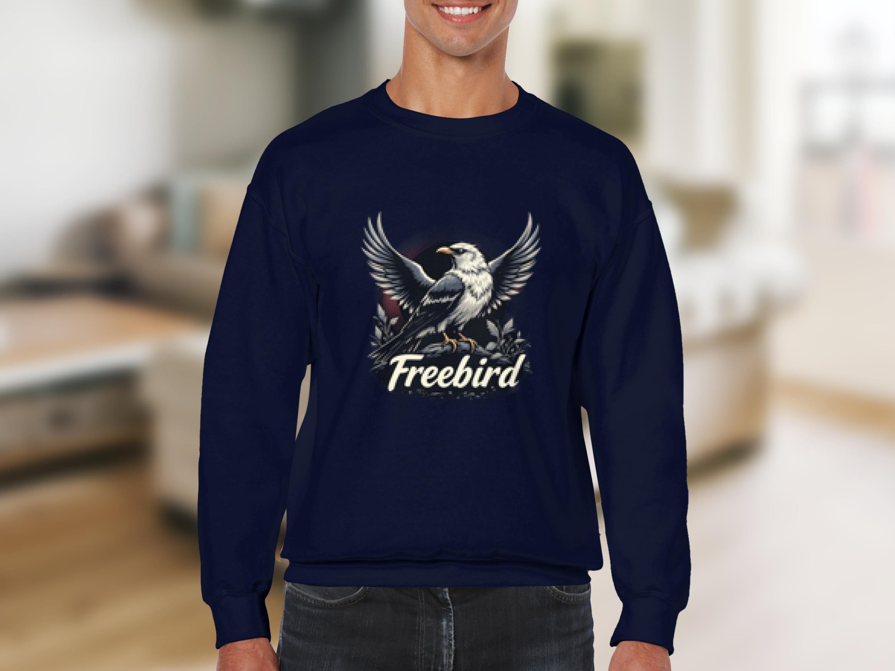 A person wears a Garment Graphics navy blue sweatshirt with an eagle and Freebird design. This unisex Freebird Graphic Sweatshirt stands out against a softly blurred indoor background, offering both style and comfort.