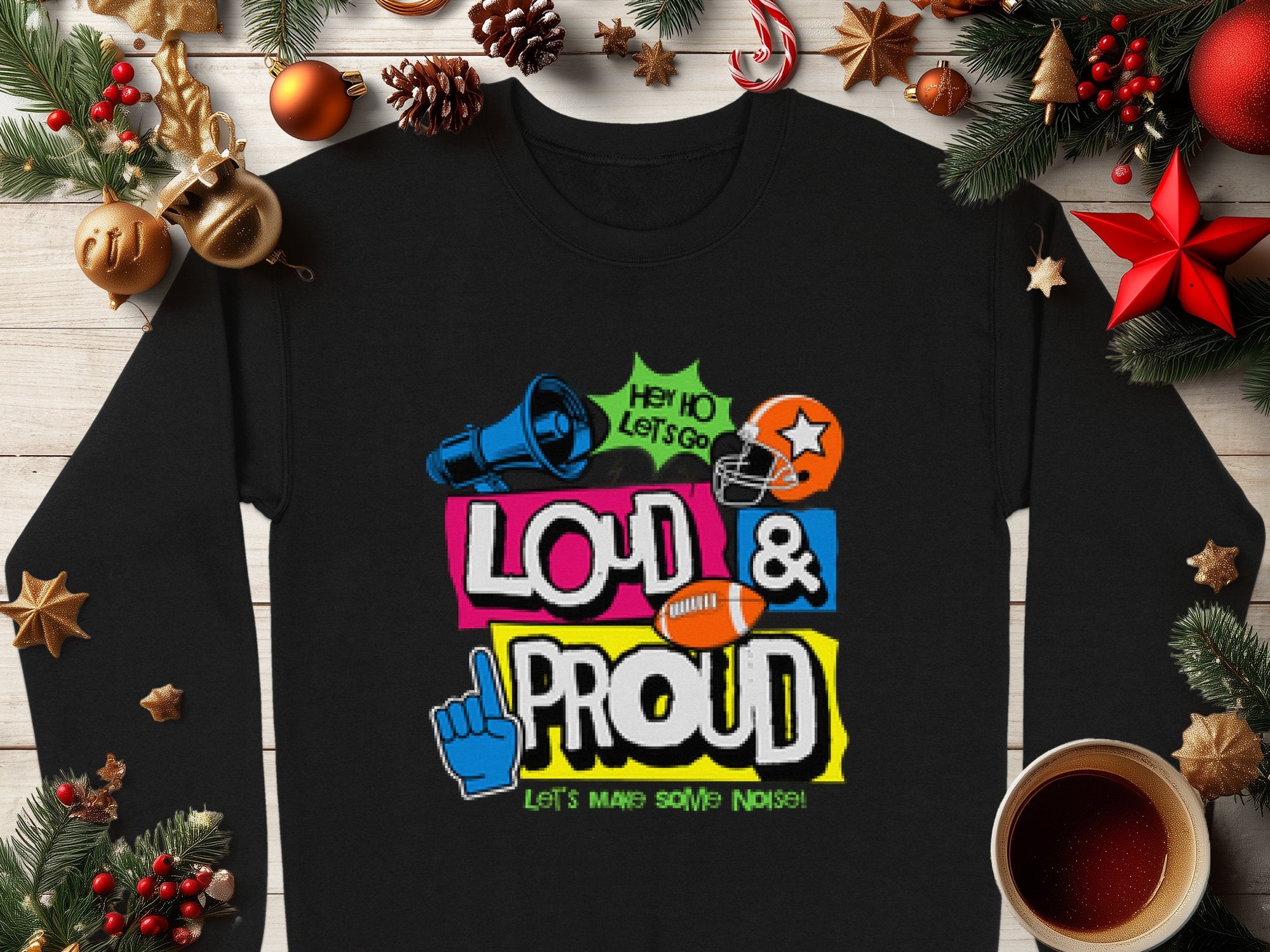 A black Garment Graphics T-shirt with vibrant HEY HO LETS GO LOUD & PROUD LETS MAKE SOME NOISE! text is displayed on wood, surrounded by festive stars, pine branches, cinnamon sticks, and coffee. Its a unique style in unisex sizing for standout fashion lovers.