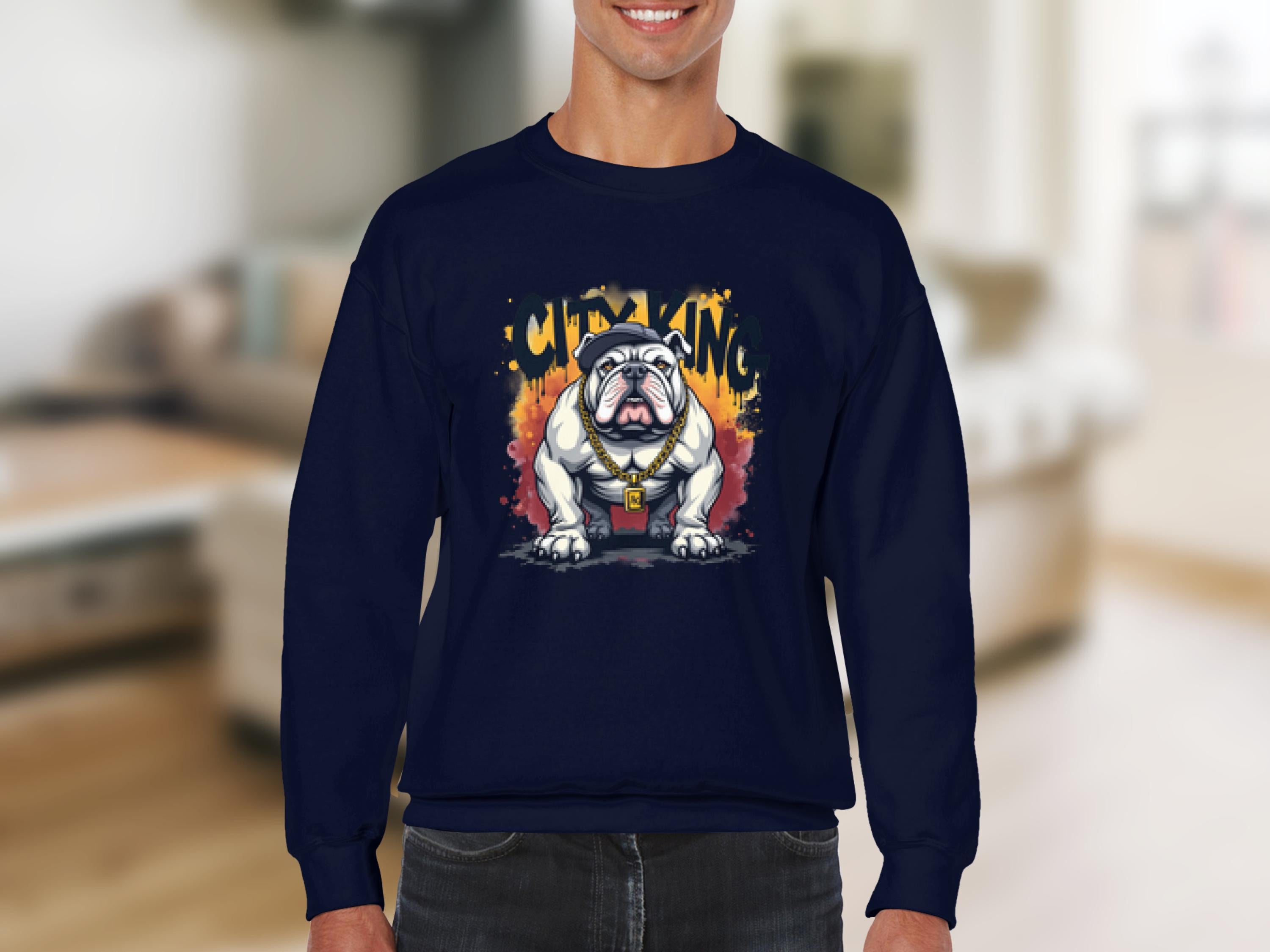 A person wears a navy blue Garment Graphics sweatshirt with a bulldog graphic featuring an orange flame background and City King text. A gold chain adds style as they stand indoors, with the room softly blurred.