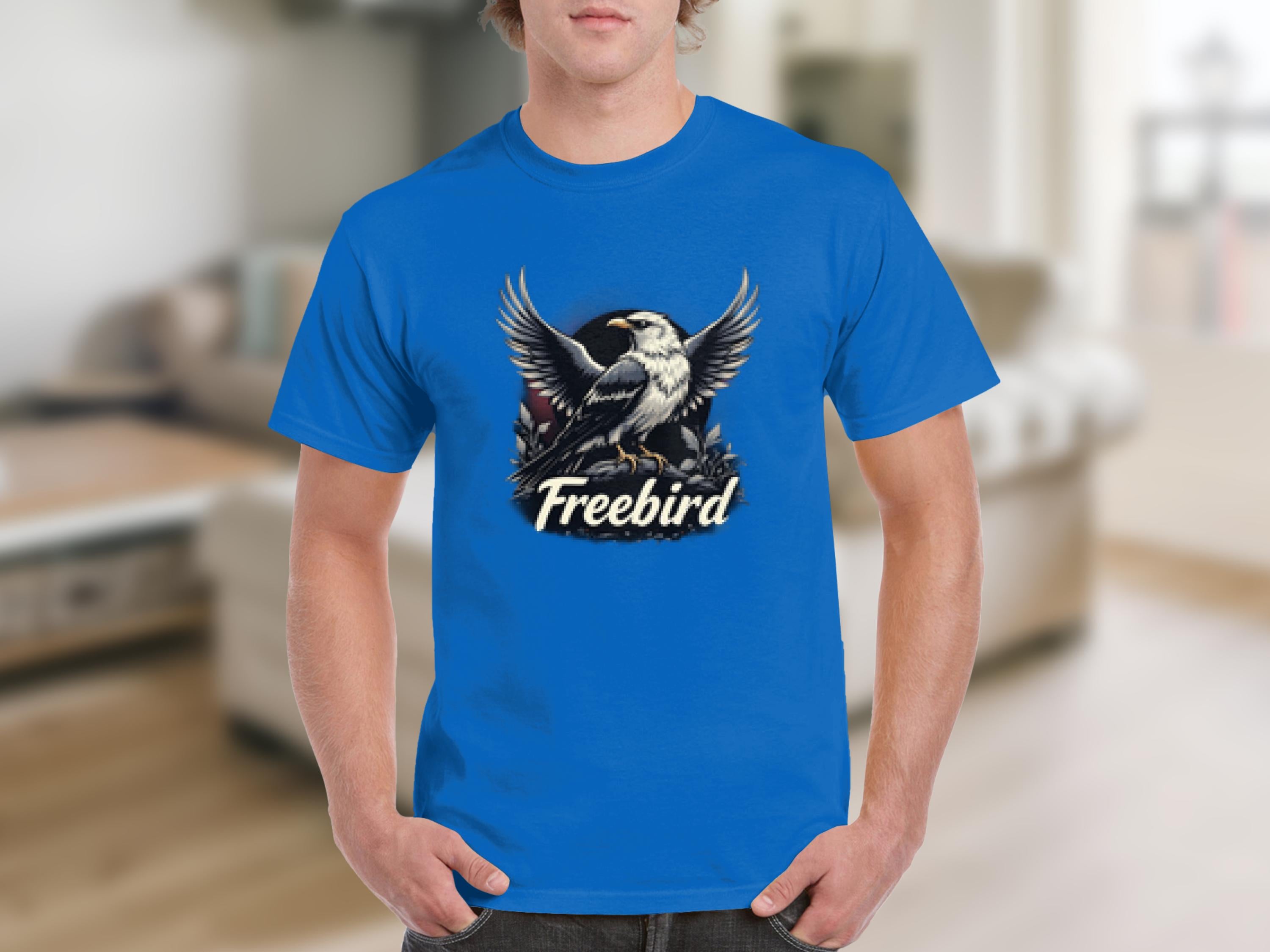 Wearing a bold, 100% cotton Garment Graphics T-shirt featuring a bird with spread wings on branches, and Freebird printed below, one evokes freedom in an out-of-focus indoor setting.