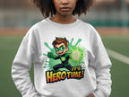 Someone is wearing a white, unisex Garment Graphics sweatshirt featuring a smiling hero character pointing and emitting a green glow. The cartoon-themed design reads Its Hero Time! and offers a perfect fit for any blurred outdoor setting.