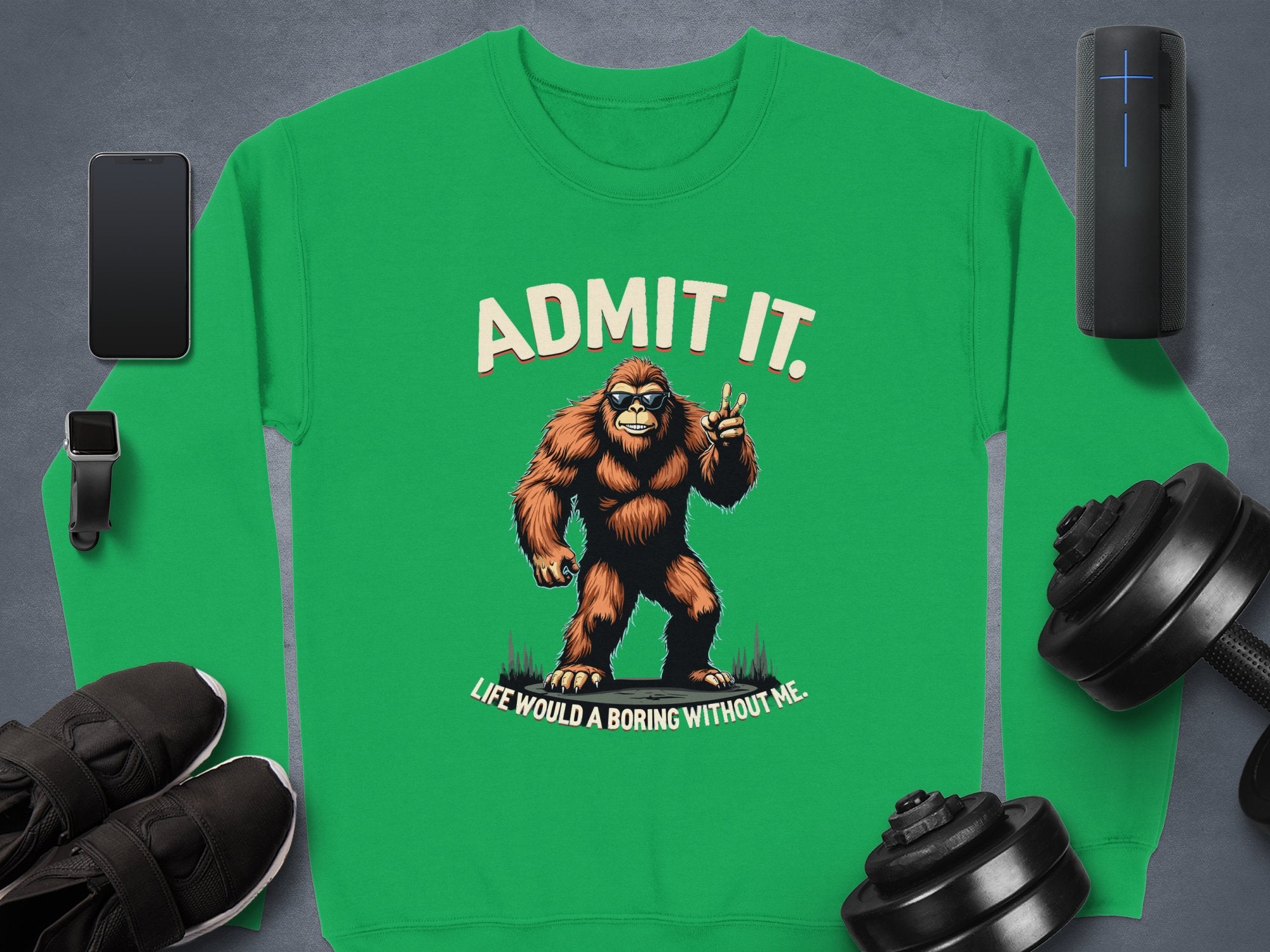 A playful Bigfoot green sweatshirt from Garment Graphics with Admit it. Life would be boring without me. is perfect for tech-savvy adventurers and pairs great with a smartphone, wireless speaker, running shoes, and dumbbells. Unisex sizing available.