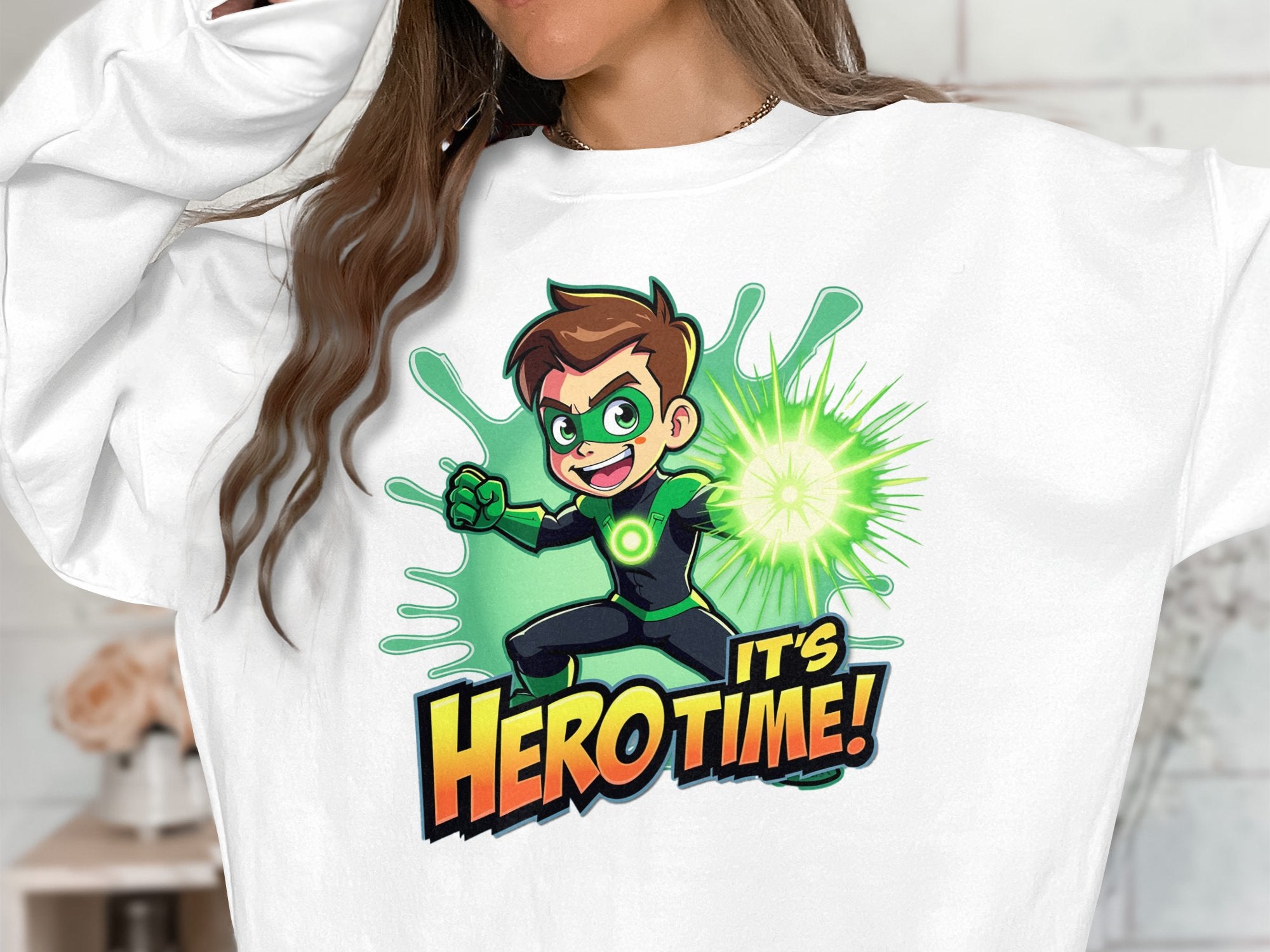 A person wearing a white unisex sweatshirt by Garment Graphics, showcasing a cartoon superhero with green accents and glowing power in hand. Its Hero Time! is prominently displayed below the character.