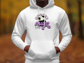 A person wears a cozy white hoodie from Garment Graphics, featuring Soccer Mum and a soccer ball graphic. The classic fit stands out in a blurred autumn outdoor scene, embodying the Soccer Mum Hoodie essence.