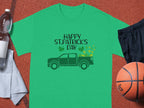 A Garment Graphics green T-shirt celebrates St. Patricks Day with Happy St. Patricks Day above an Irish pride pickup truck and shamrocks, paired with a water bottle, towel, black shorts, and orange basketball for a festive sporty look.