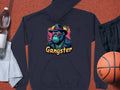 This black hoodie by Garment Graphics features a smokey cool cartoon gorilla wearing a hat and sunglasses with Gangster below. Its perfect paired with essentials like a water bottle, towel, black shorts, and basketball, crafted from medium-heavy fabric for comfort.