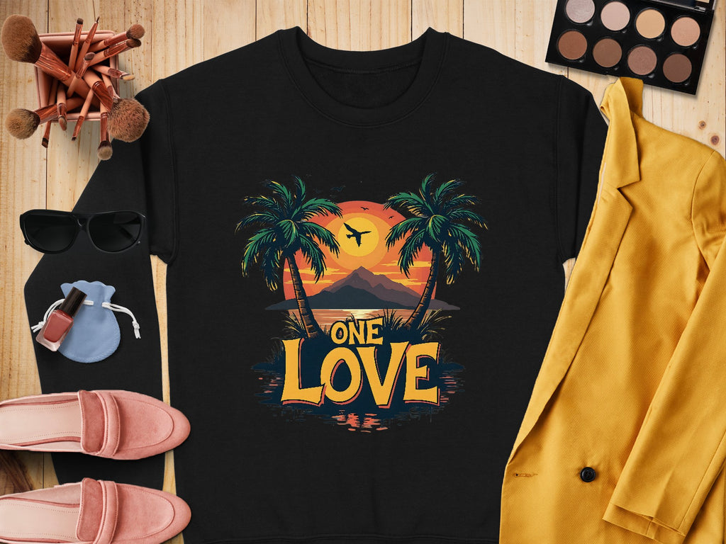Flat lay showcasing a black Garment Graphics shirt with a vibrant One Love Sunset palm tree design, complemented by a yellow blazer, eyeshadow palette, makeup brushes, sunglasses, red lipstick, blue pouch, and pink shoes—all artfully arranged on a wooden surface.