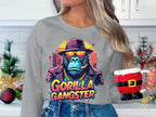 A person in an urban style Garment Graphics gray sweatshirt, featuring a vibrant Gorilla Gangster with sunglasses and a hat, holds a mug designed like Santas outfit. The kitchen is decorated festively.