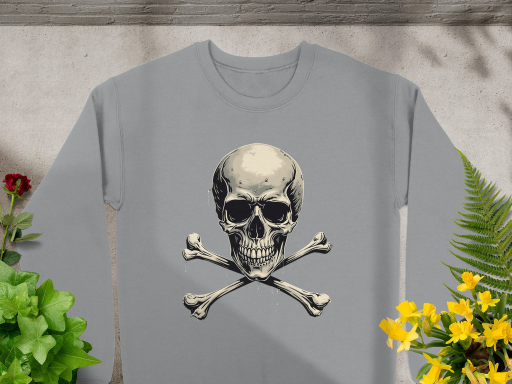 The Garment Graphics unisex gray sweatshirt features an edgy skull and crossbones design, encircled by vivid green leaves, a red rose on the left, yellow flowers on the right, and a fern at the bottom right. Its textured background adds dimension.