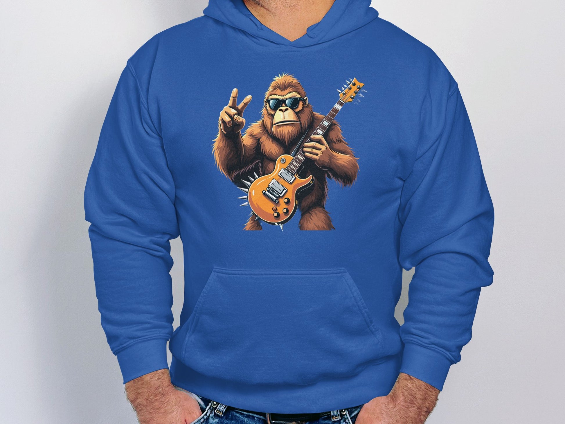 The Garment Graphics blue hoodie boasts a cartoon gorilla with sunglasses, rocking an orange electric guitar and a peace sign. Its the perfect choice for music and animal enthusiasts who will enjoy the Guitar Playing Gorilla design.