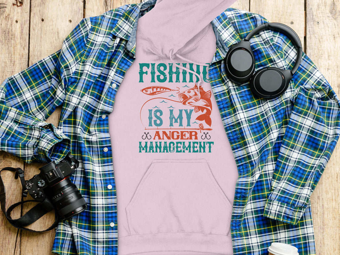 A person wearing a black hoodie from Garment Graphics featuring the text Fishing is my anger management in teal and orange. With a fish graphic, this Anglers Wardrobe piece is perfect for any fishing enthusiast.