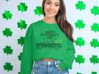 Wearing a Garment Graphics festive green sweatshirt with a Happy St. Patricks Day message and truck design, a person stands out among shamrocks. With long hair, a smile, and one hand tucked in their pocket, they perfectly capture the holiday spirit.