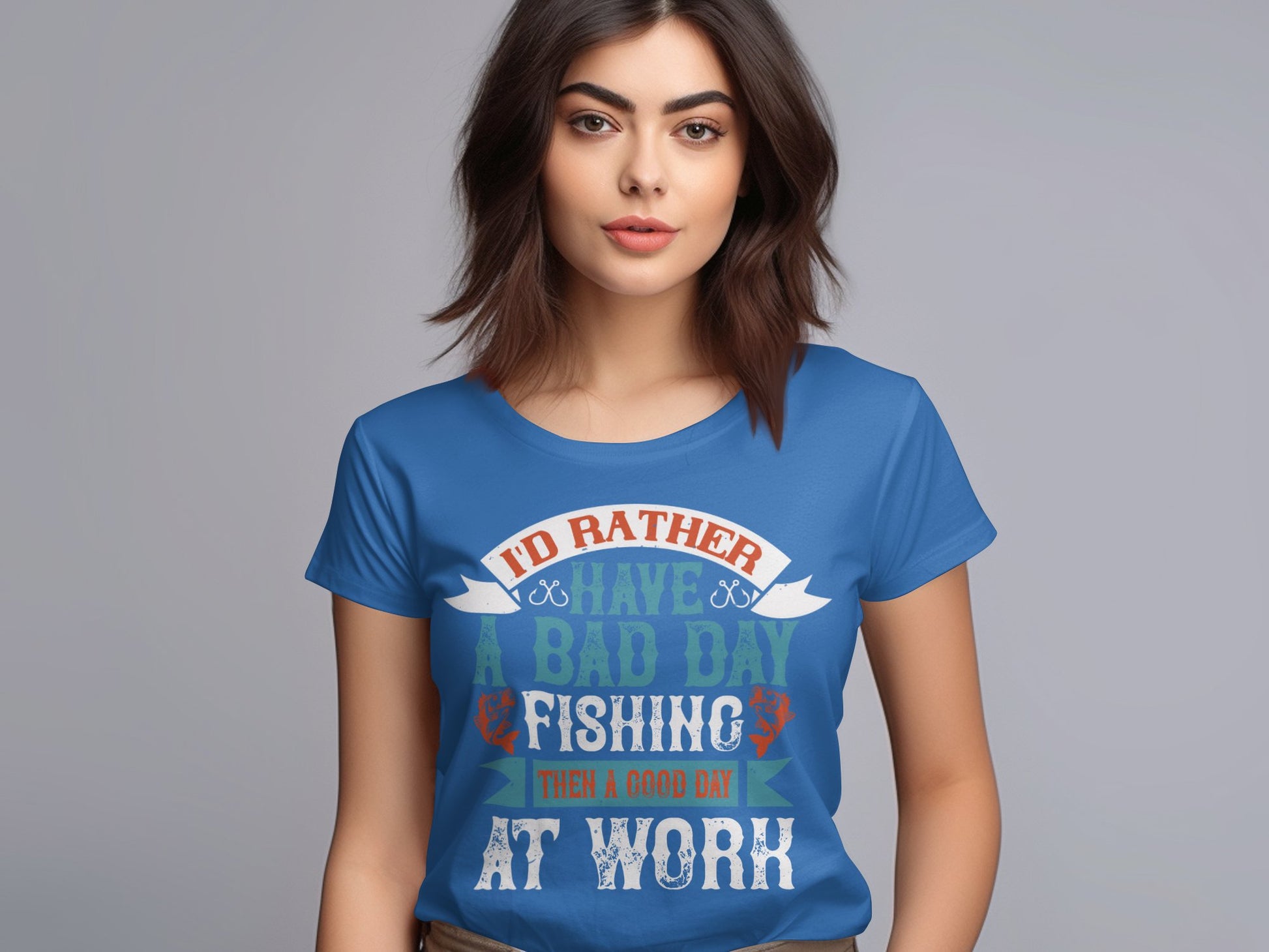 A fishing enthusiast with long dark hair wears a blue Id Rather Have a Bad Day Fishing Than a Good Day at Work T-shirt by Garment Graphics, tailored for women. The shirt features a colorful design and she stands against a neutral gray background.