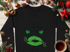 The Garment Graphics black sweatshirt showcases a green lips print with Happy St. Patricks Day text, clover kisses, and shamrocks. Set on wood with festive decor, pinecones, and a coffee cup, it exudes a perfect festive spirit.