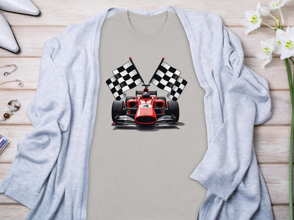 A Garment Graphics gray T-shirt displaying a red racing car and two checkered flags captures the motorsport thrill. Its laid on wood and paired with a light blue cardigan adorned with white and pink flowers on the right.
