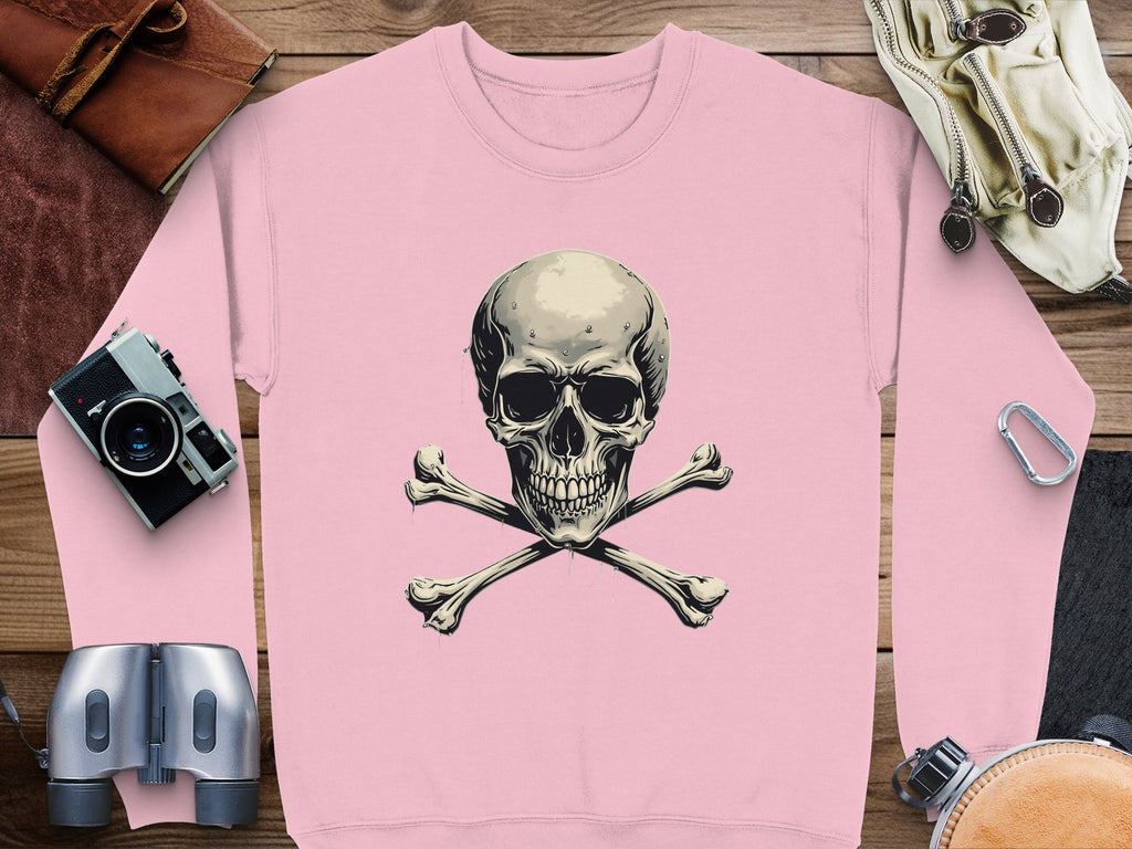 Garment Graphics pink sweatshirt features a striking skull and crossbones design for an edgy look. Its displayed on wood with a camera, binoculars, leather bag, carabiner, and hiking gloves. Unisex sizing offers versatile style.