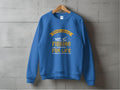 A blue sweatshirt by Garment Graphics hangs on a wooden hanger against a concrete wall, featuring a yellow and white Father and Son Fishing Partners for Life design, complete with charming illustrations of a boat and fish.