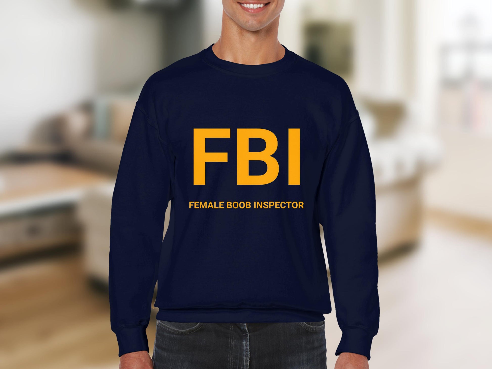 A person wears a navy blue Garment Graphics sweatshirt in unisex sizing with bold yellow text FBI and the smaller text FEMALE BOOB INSPECTOR below it, set against a softly blurred indoor backdrop.